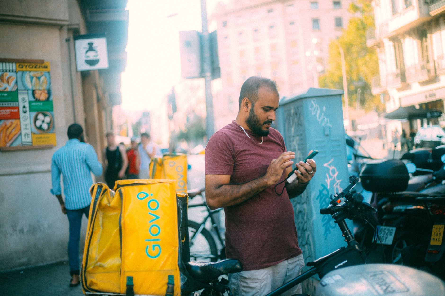 Delivery courier checking earnings on smartphone on a sunny urban street